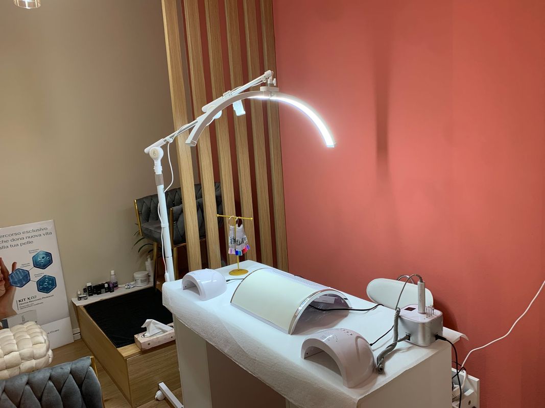 Sala per visite mediche con lettino per pazienti, lampada curva e attrezzature bianche accanto a una parete color corallo.