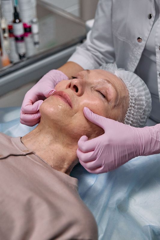 In un ambulatorio, delle mani guantate massaggiano il viso di un paziente anziano.