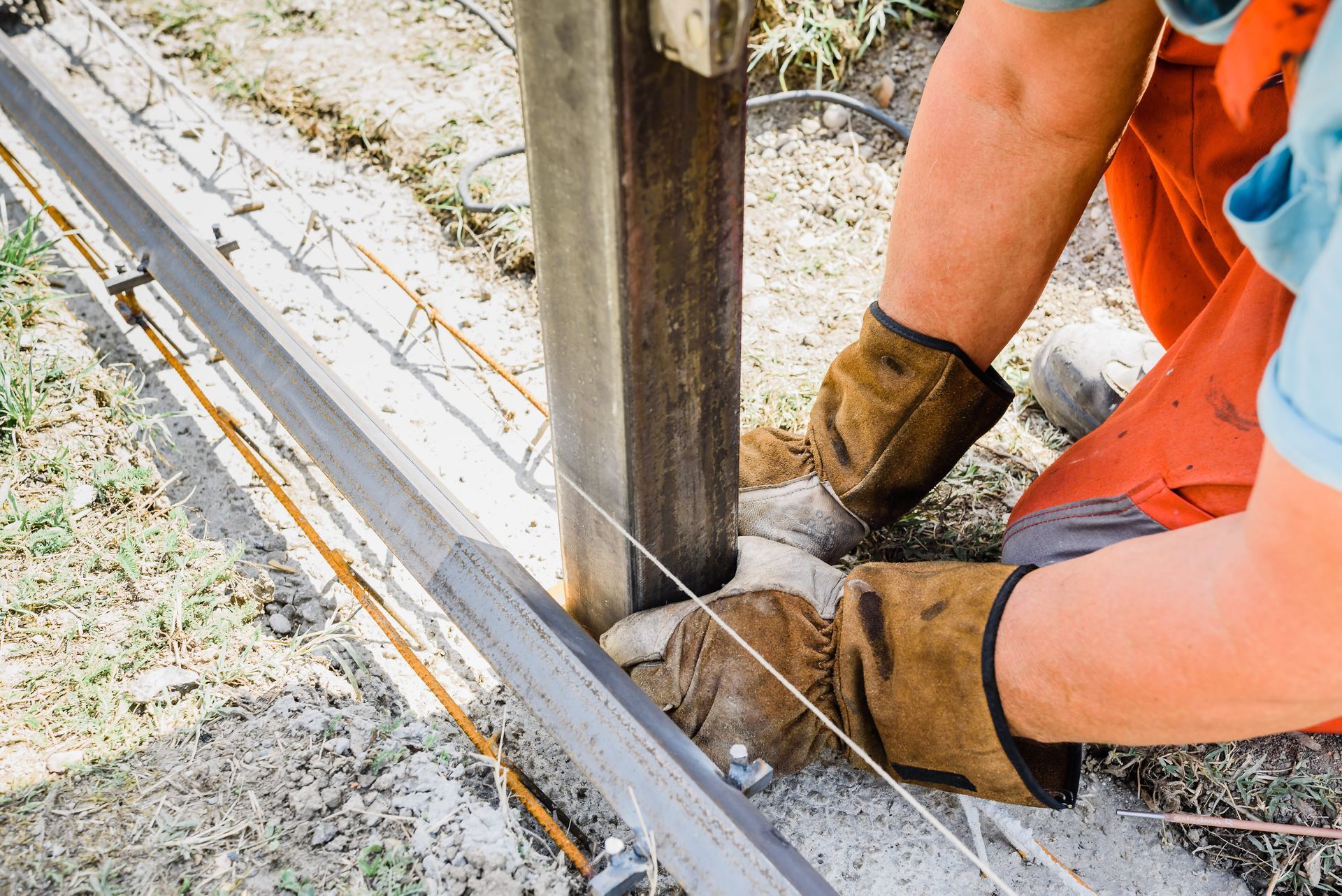Person wearing gloves working on metal construction outdoors. Person wearing gloves working on metal construction outdoors.