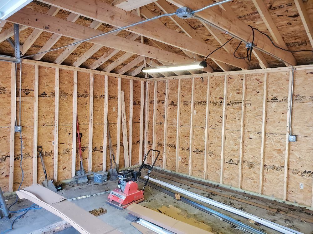 Two people constructing a wooden garage frame in a yard with snow, near a fence and houses. Two people constructing a wooden garage frame in a yard with snow, near a fence and houses.