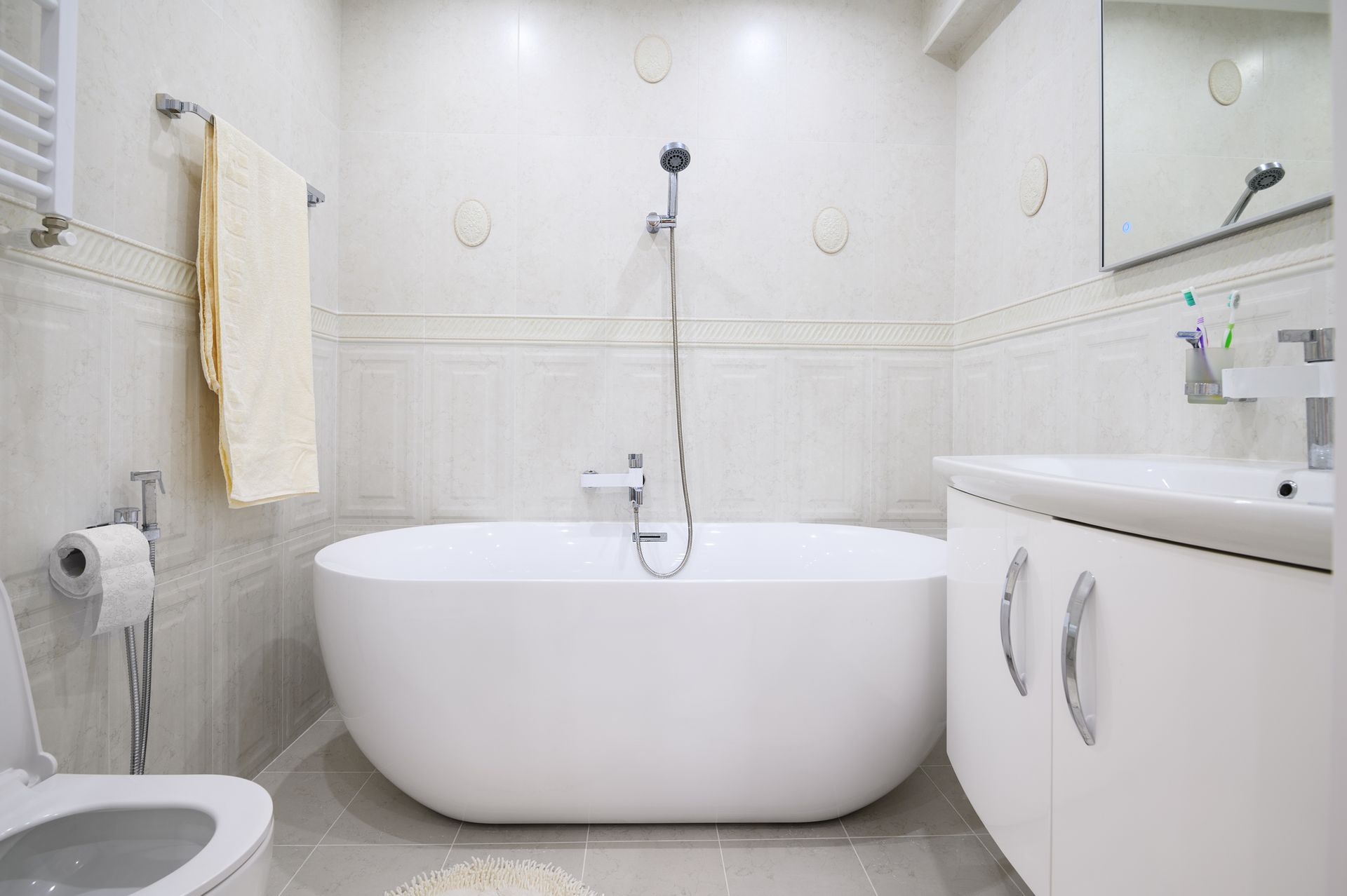Modern white bathroom with a bathtub, toilet, sink, and towel rack. Modern white bathroom with a bathtub, toilet, sink, and towel rack.