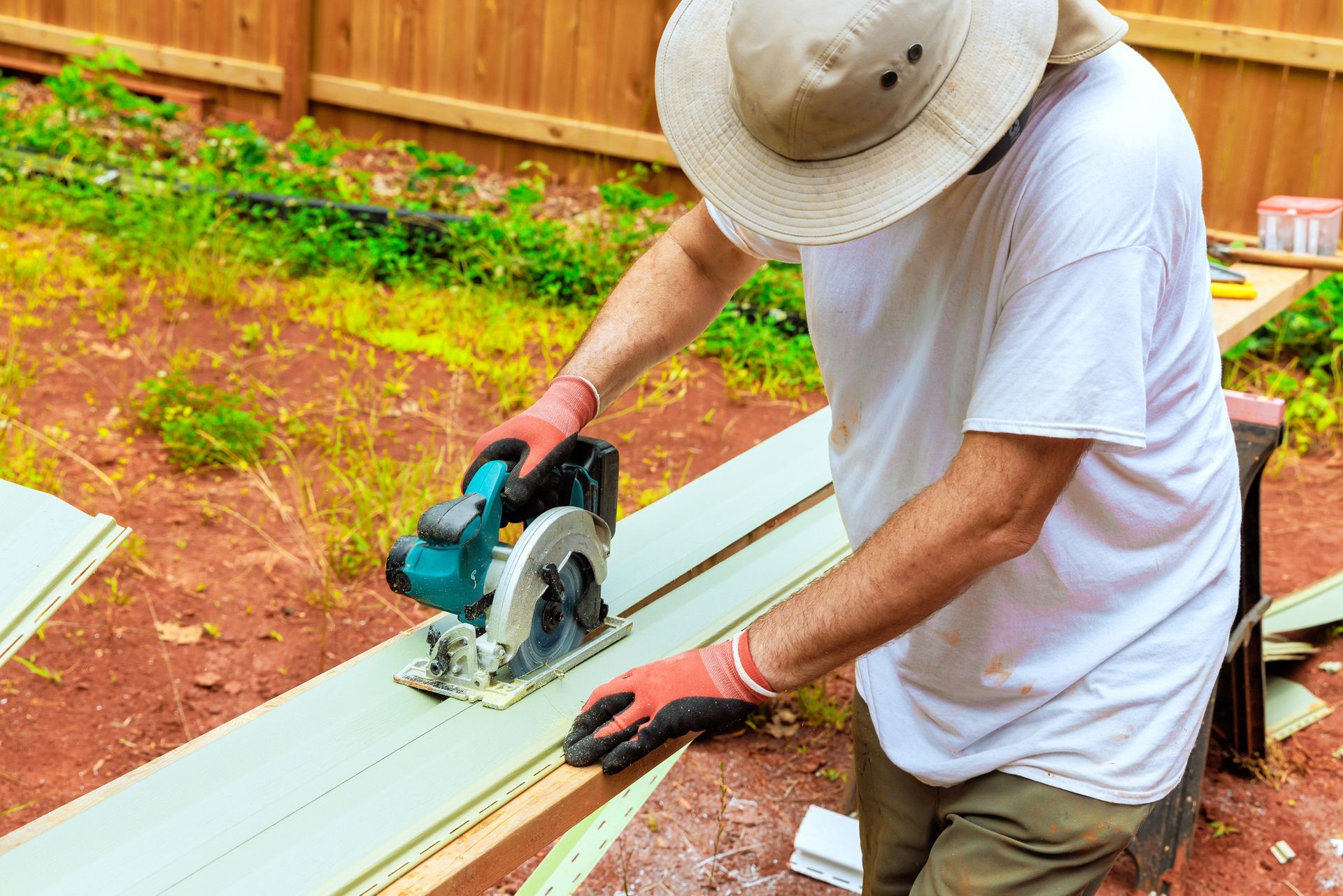 Person in hat using a circular saw to cut wood outdoors. Person in hat using a circular saw to cut wood outdoors.