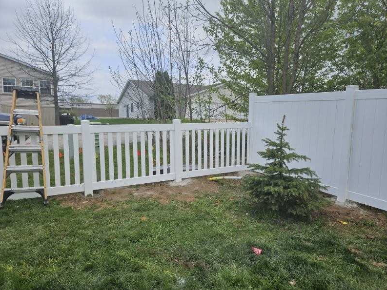 White picket fence with decorative finials along a tree-lined street. White picket fence with decorative finials along a tree-lined street.