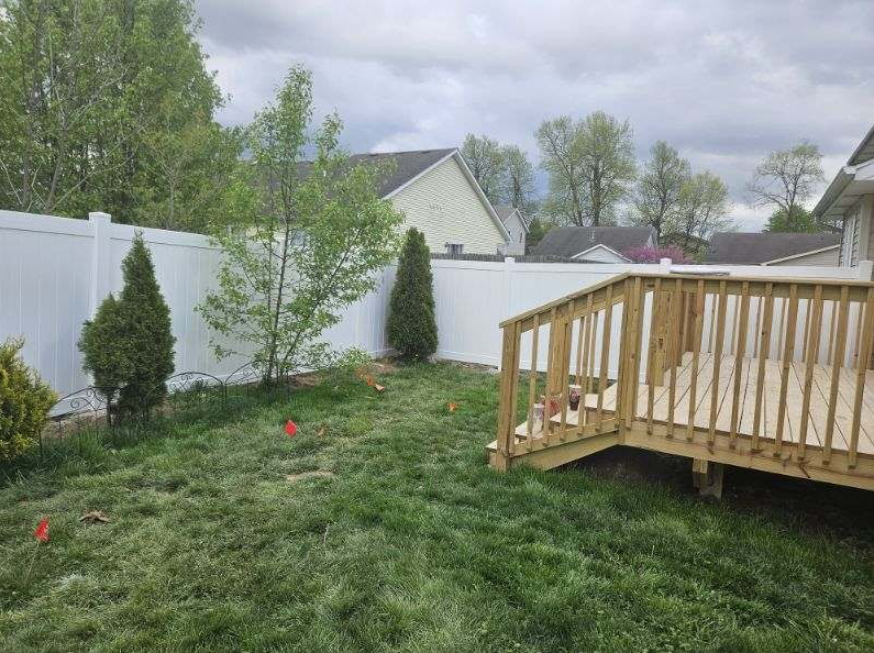 A person in red gloves painting a white picket fence with a paintbrush outdoors. A person in red gloves painting a white picket fence with a paintbrush outdoors.