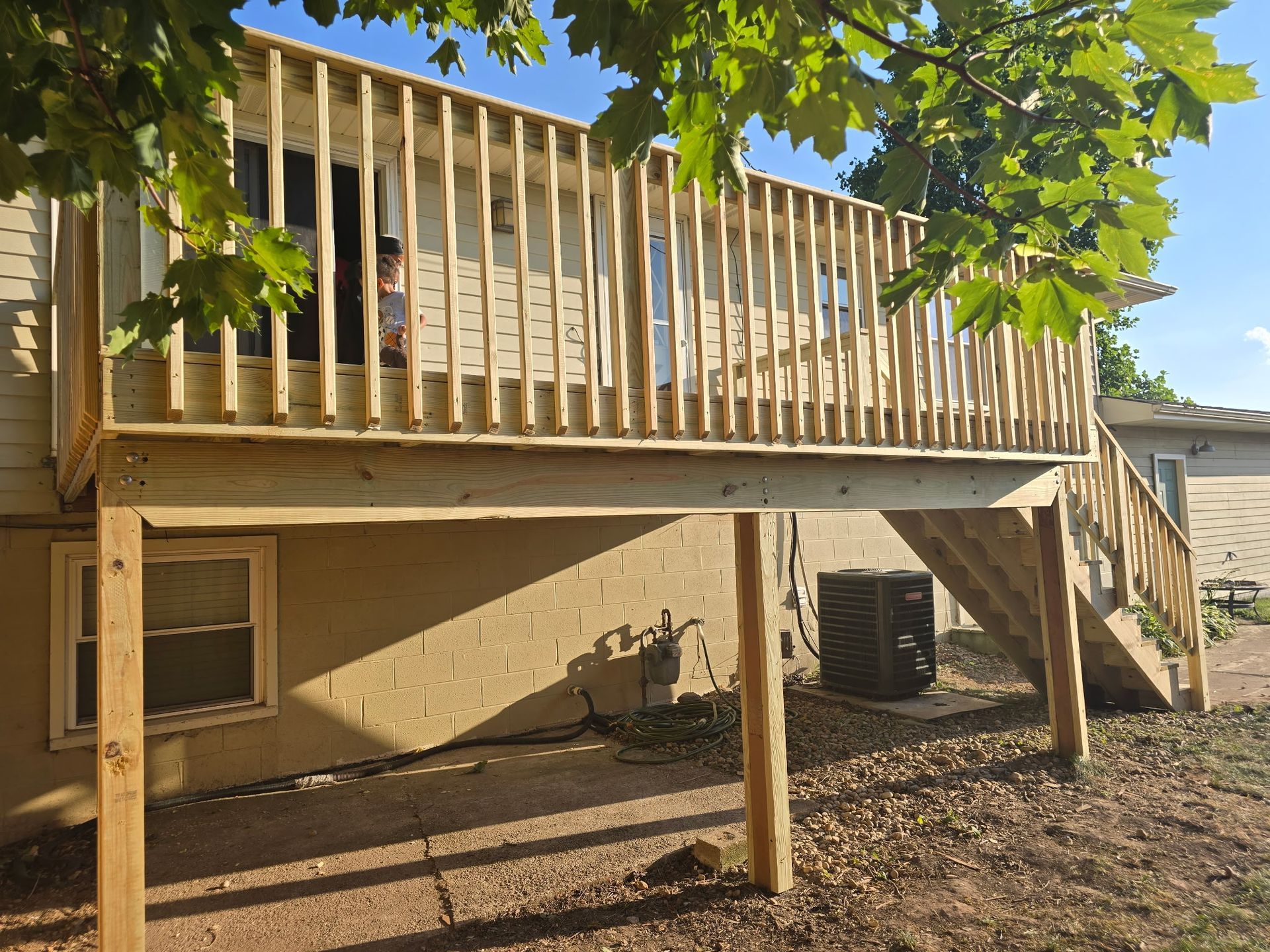 Wooden deck on the back of a house with railing. Sunlight, exterior.
