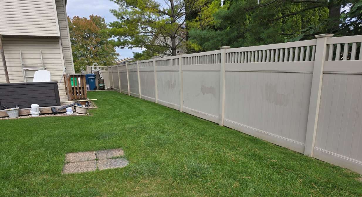 Man uses a level to install wooden fence panels outdoors. Man uses a level to install wooden fence panels outdoors.