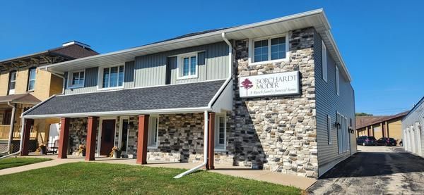 Two-story building with a stone-accented facade, dark roof, and a sign for 
