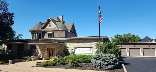 A stone and wood building with a dark shingled roof, a three-car garage, and an American flag flying on a clear day.