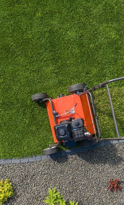 An aerial view of a lawn mower cutting a lush green lawn.