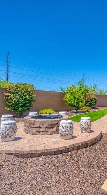 There is a fire pit in the middle of the backyard surrounded by stools.
