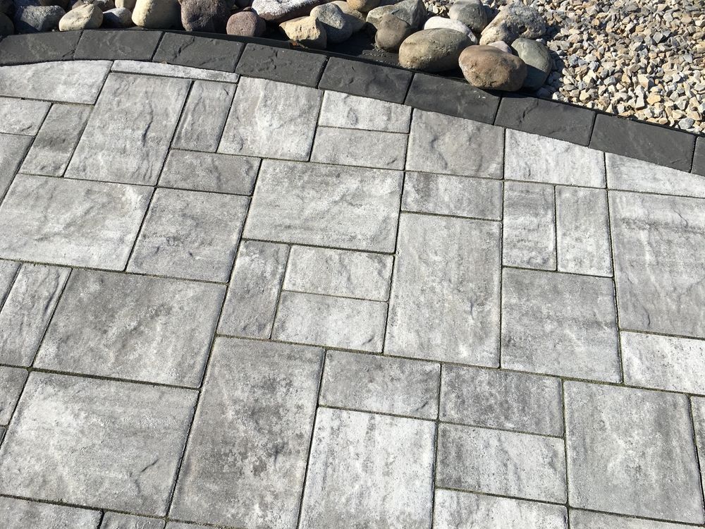 A close up of a brick walkway with rocks in the background.