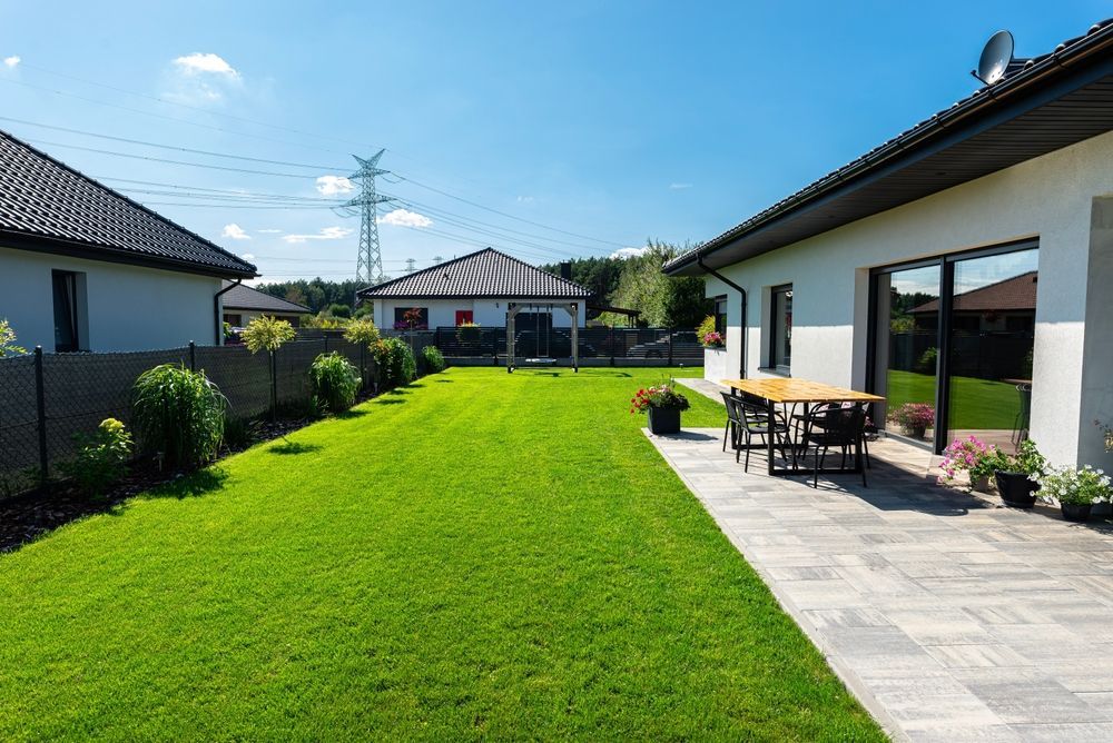There is a patio in the backyard of a house with a table and chairs.