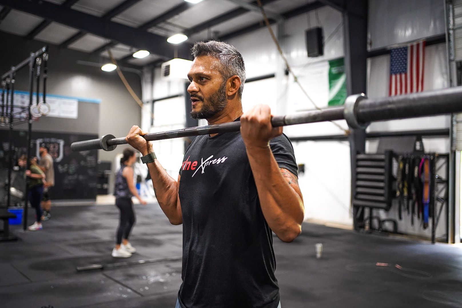 A man is lifting a barbell over his head in a gym.