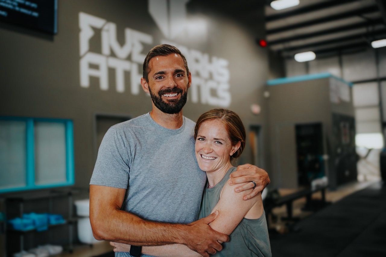 A man and a woman are posing for a picture in a gym.