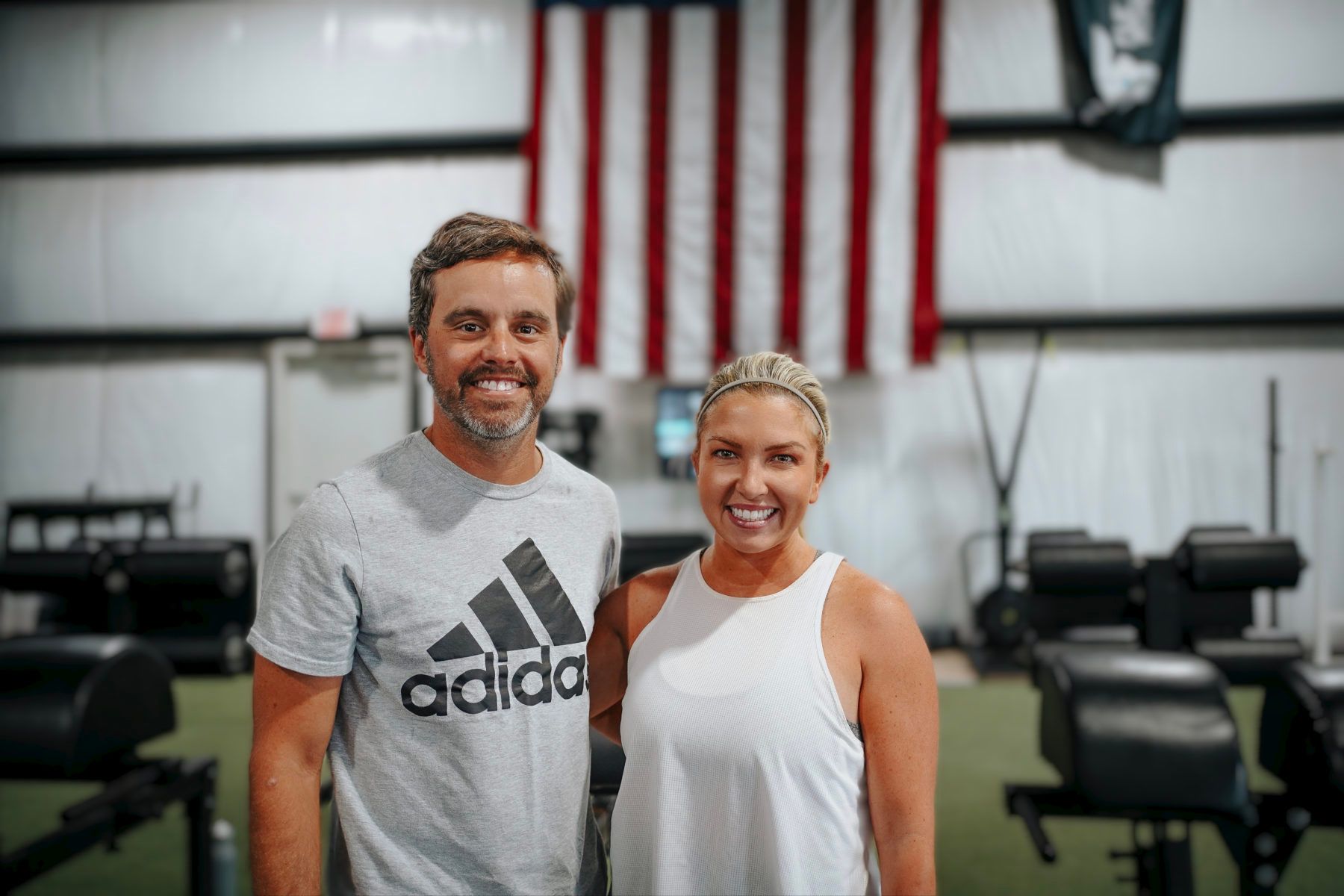A man and a woman are posing for a picture in a gym.