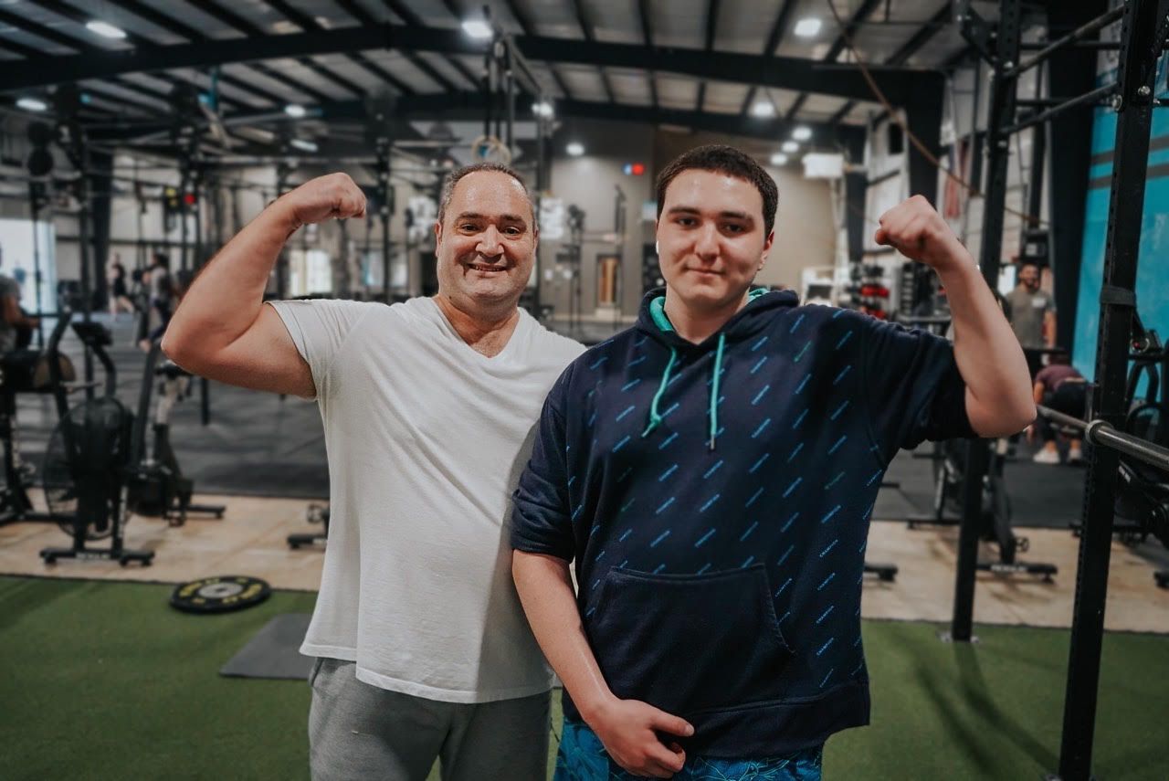 Two men are flexing their muscles in a gym.
