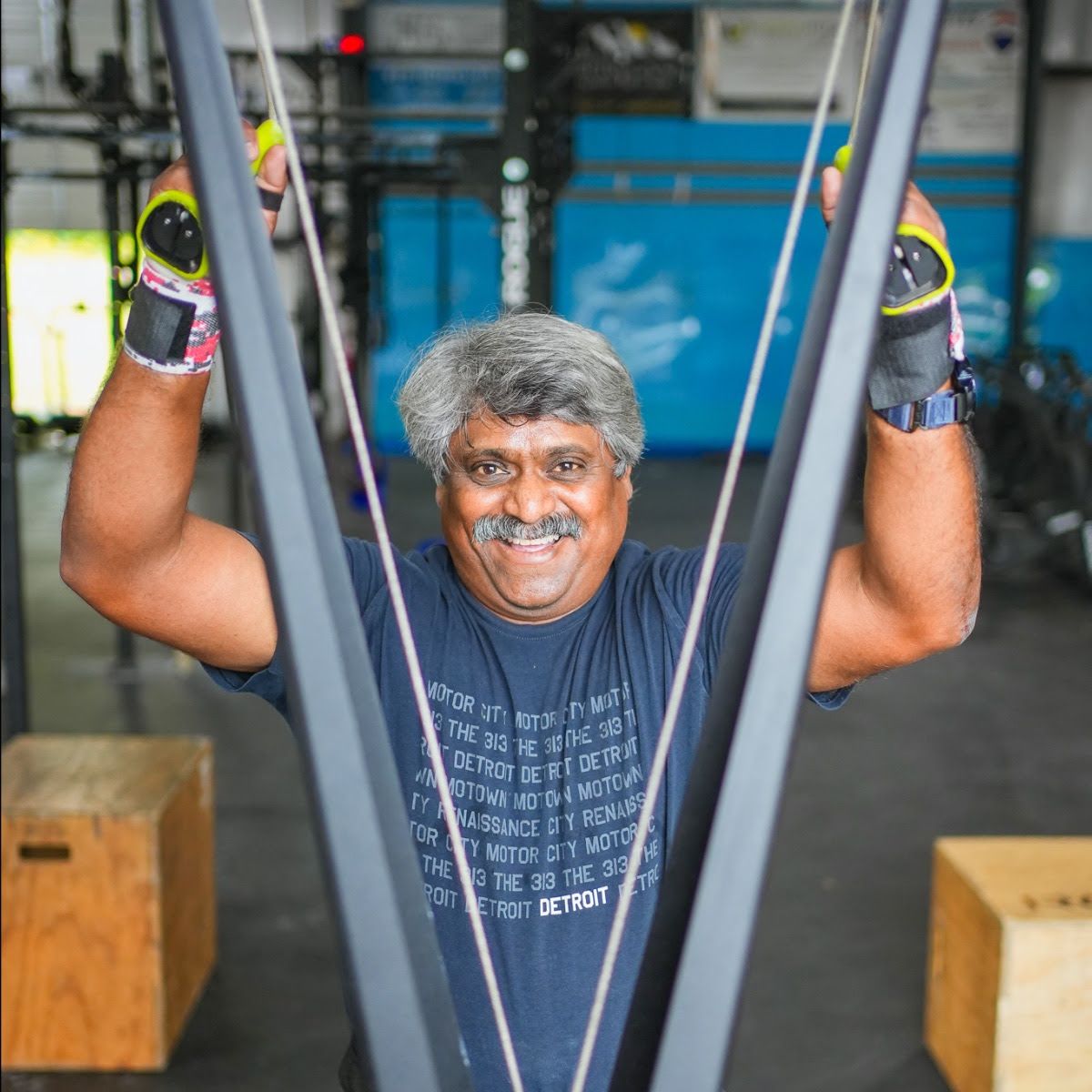 A man wearing a born primitive t-shirt is standing in a gym.