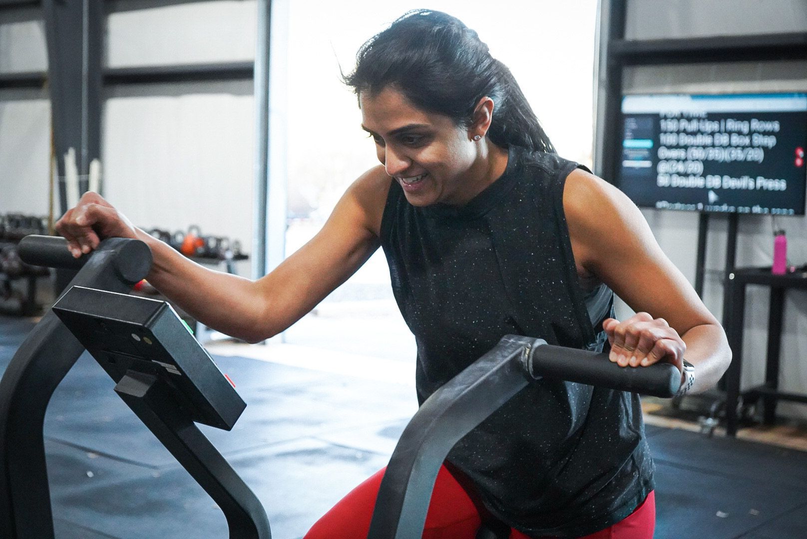 A woman is riding an exercise bike in a gym.