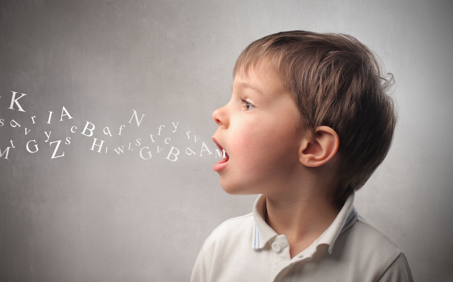 A young boy is talking with letters coming out of his mouth.