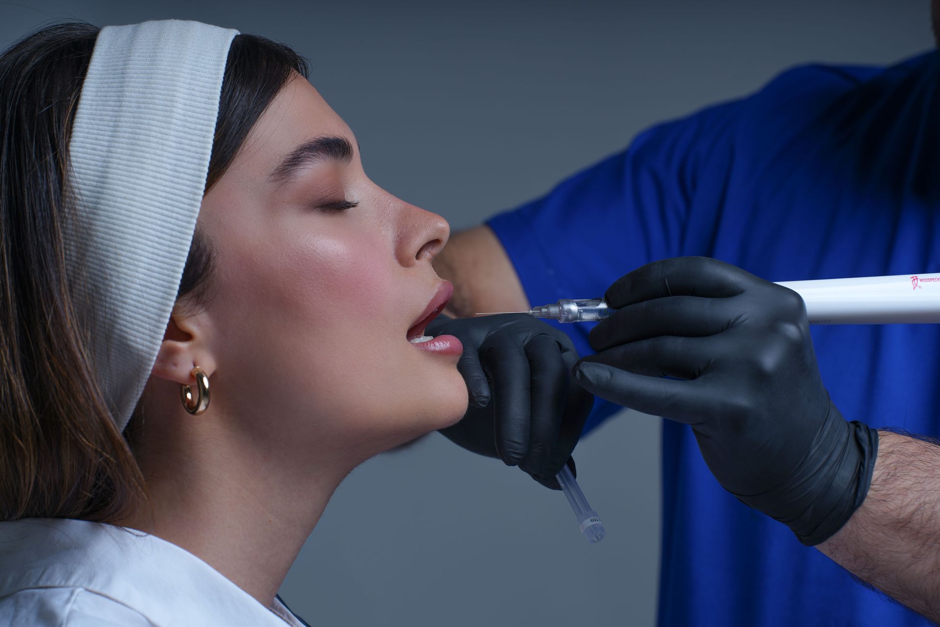 Dentist applying treatment to a patient with a syringe, close-up side view