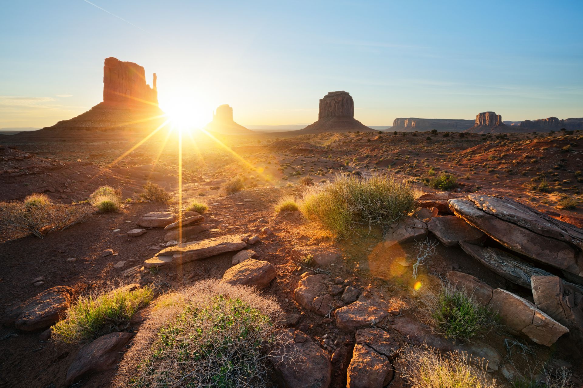 Sunrise over a rocky desert landscape with mesas and warm golden light