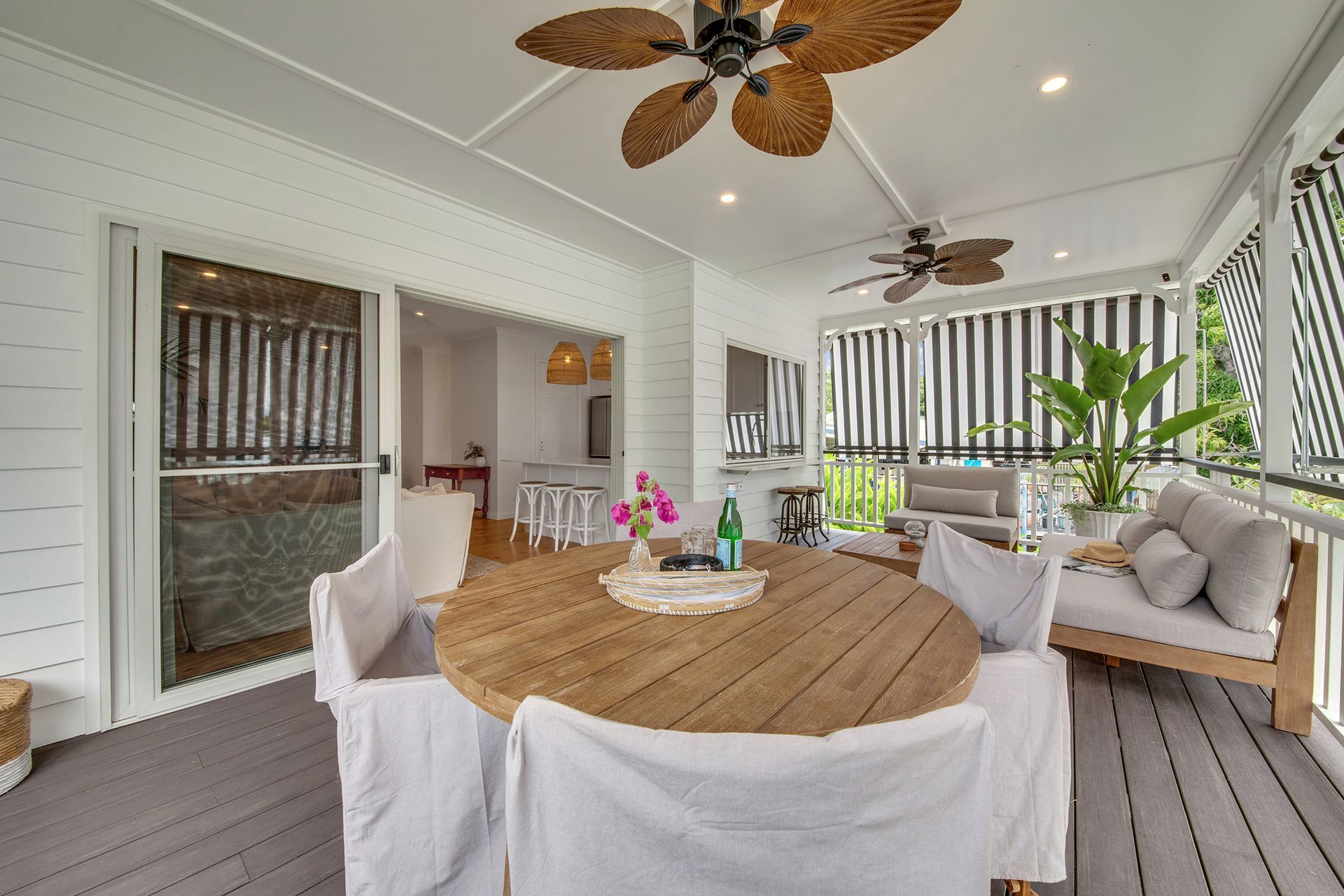 Covered Porch With Round Wooden Dining Table and Seating — Wares Blinds, Screens & Awnings In Agnes Water, QLD