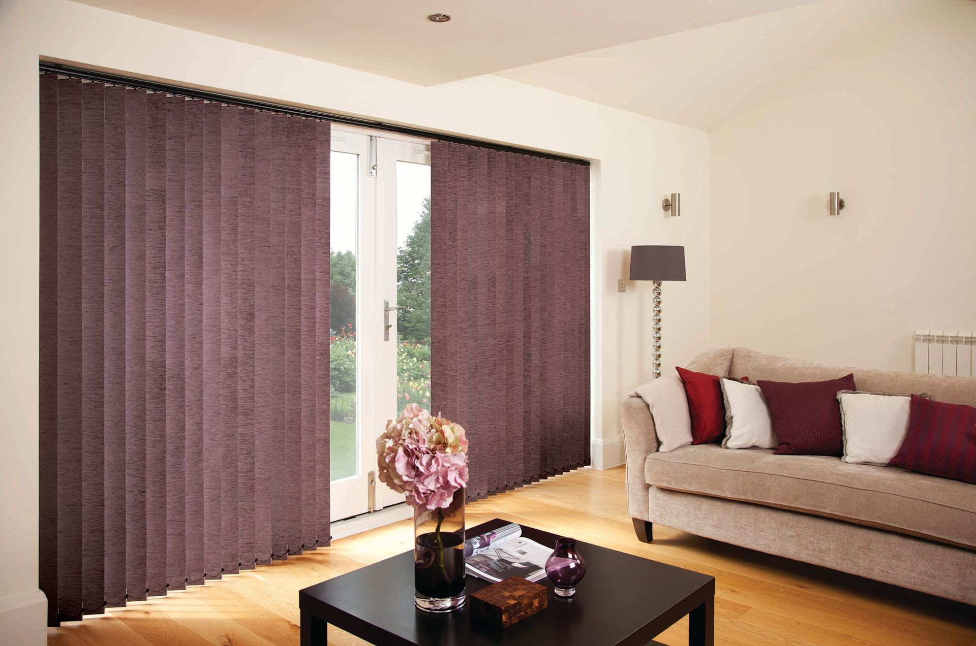 Living room with vertical purple blinds covering patio doors, sofa, coffee table.