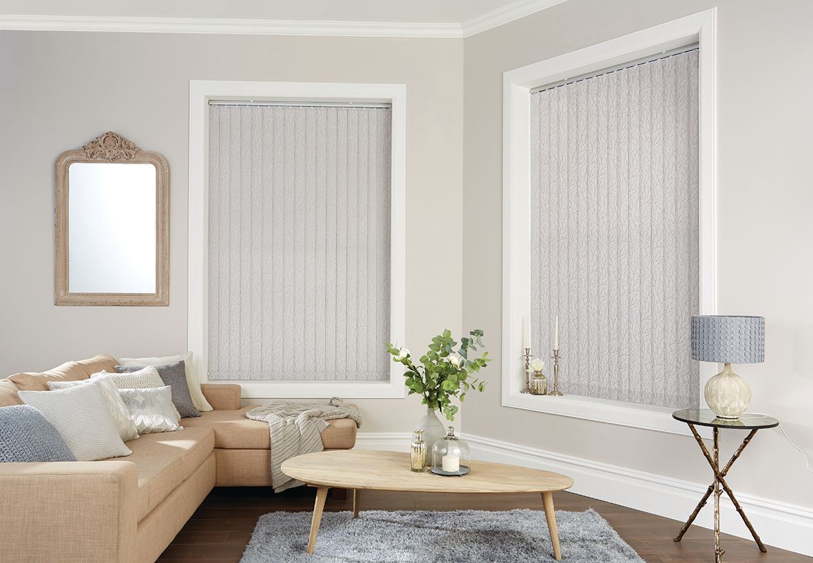 Living room with beige walls, corner couch, vertical blinds, mirror, small table, and rug.