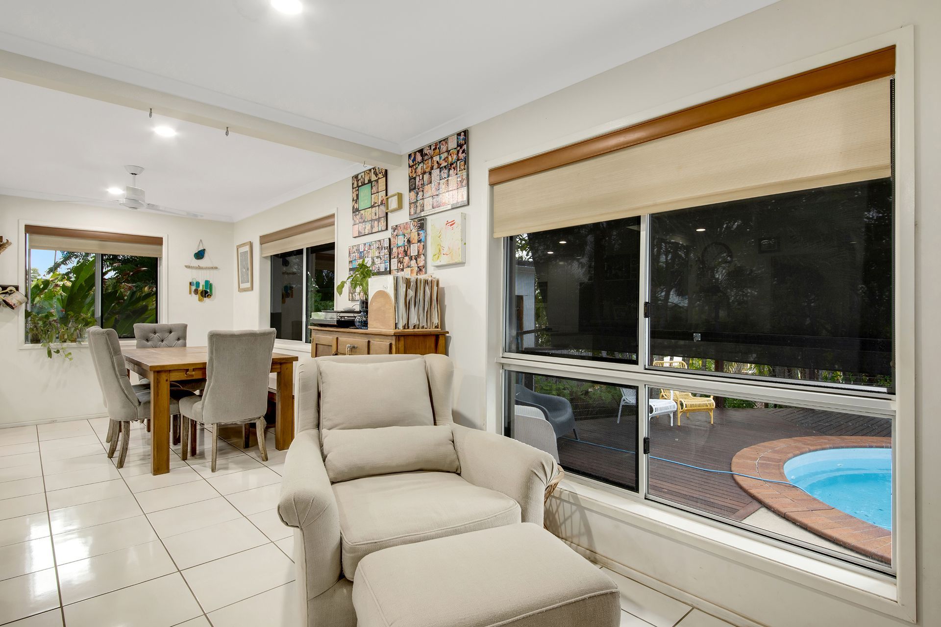 Living Room with Armchair, Dining Table, and Pool View Through a Large Window — Wares Blinds, Screens & Awnings In Gladstone Central, QLD