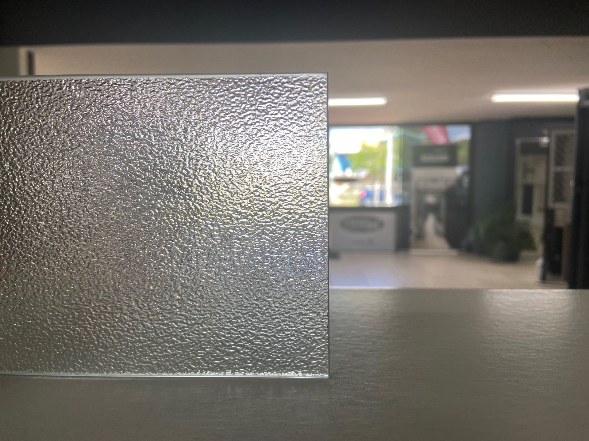 Textured Glass Pane on a Gray Surface With Blurred Interior in the Background — Wares Blinds, Screens & Awnings In Gladstone Central, QLD