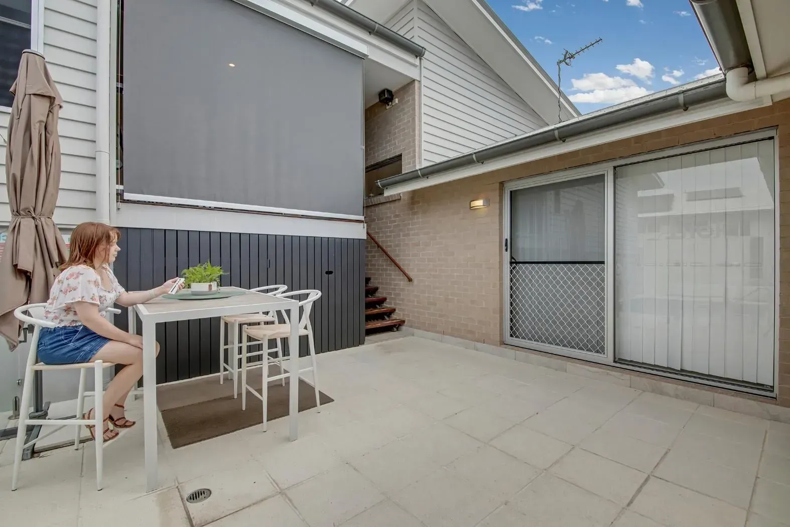 Woman at Table on Patio with Sliding Door — Wares Blinds, Screens & Awnings In Rockhampton, QLD