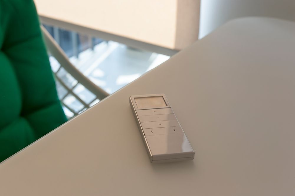 White Remote on a White Table. Green Chair in the Background — Wares Blinds, Screens & Awnings In Gladstone Central, QLD