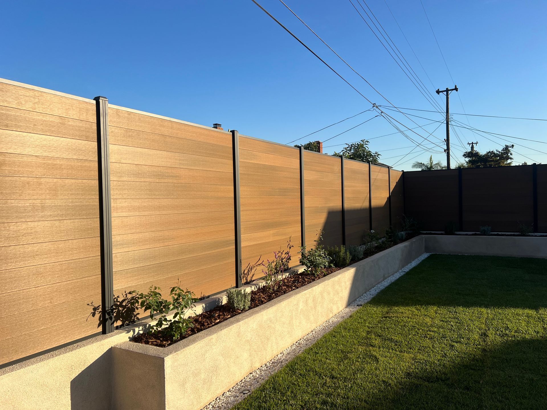 A wooden fence surrounds a lush green yard