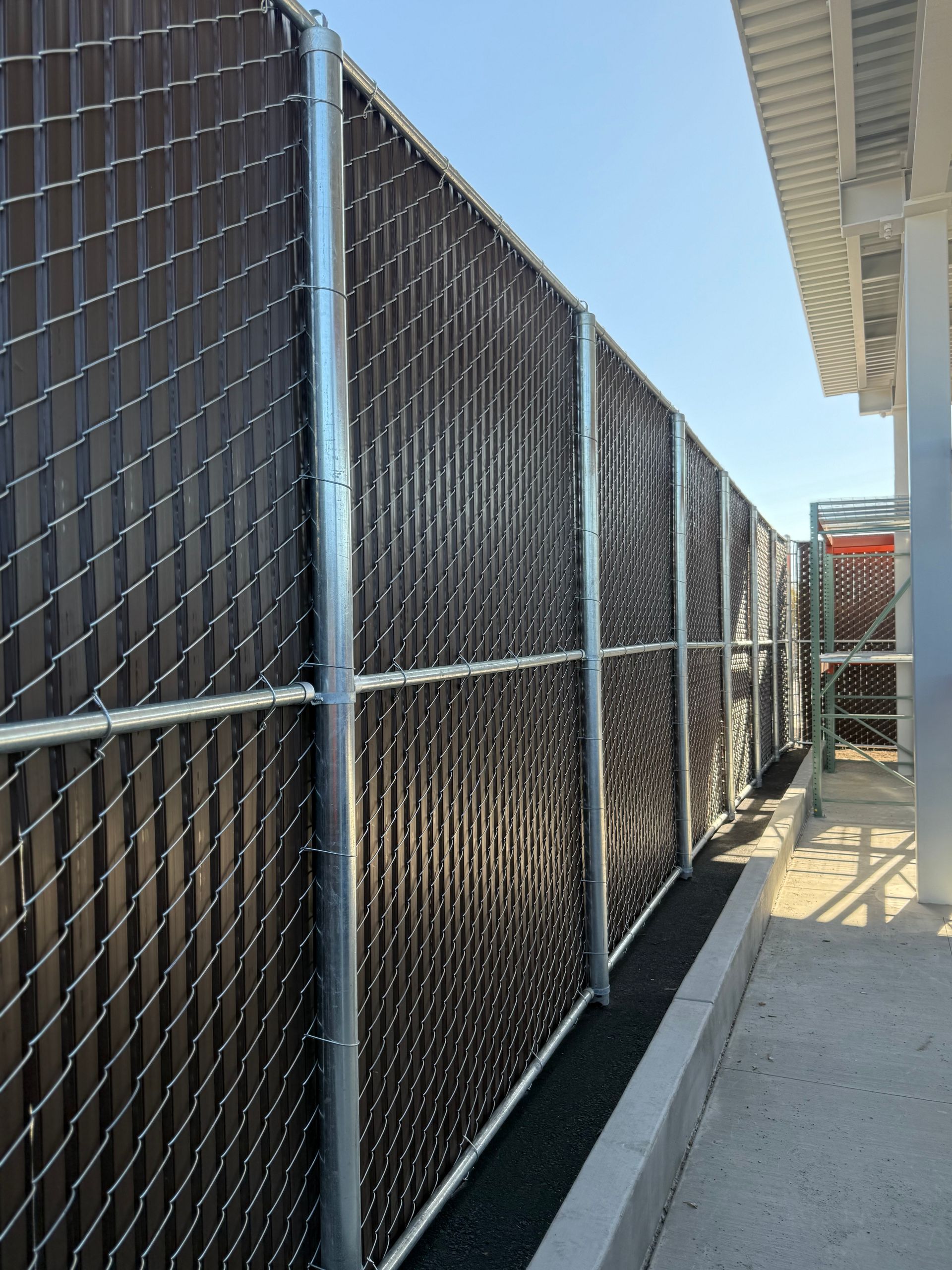 A chain link fence with a brown slat on it