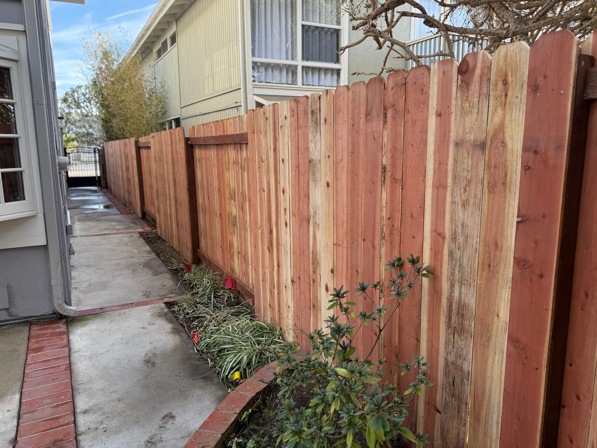 A wooden fence along a sidewalk next to a house