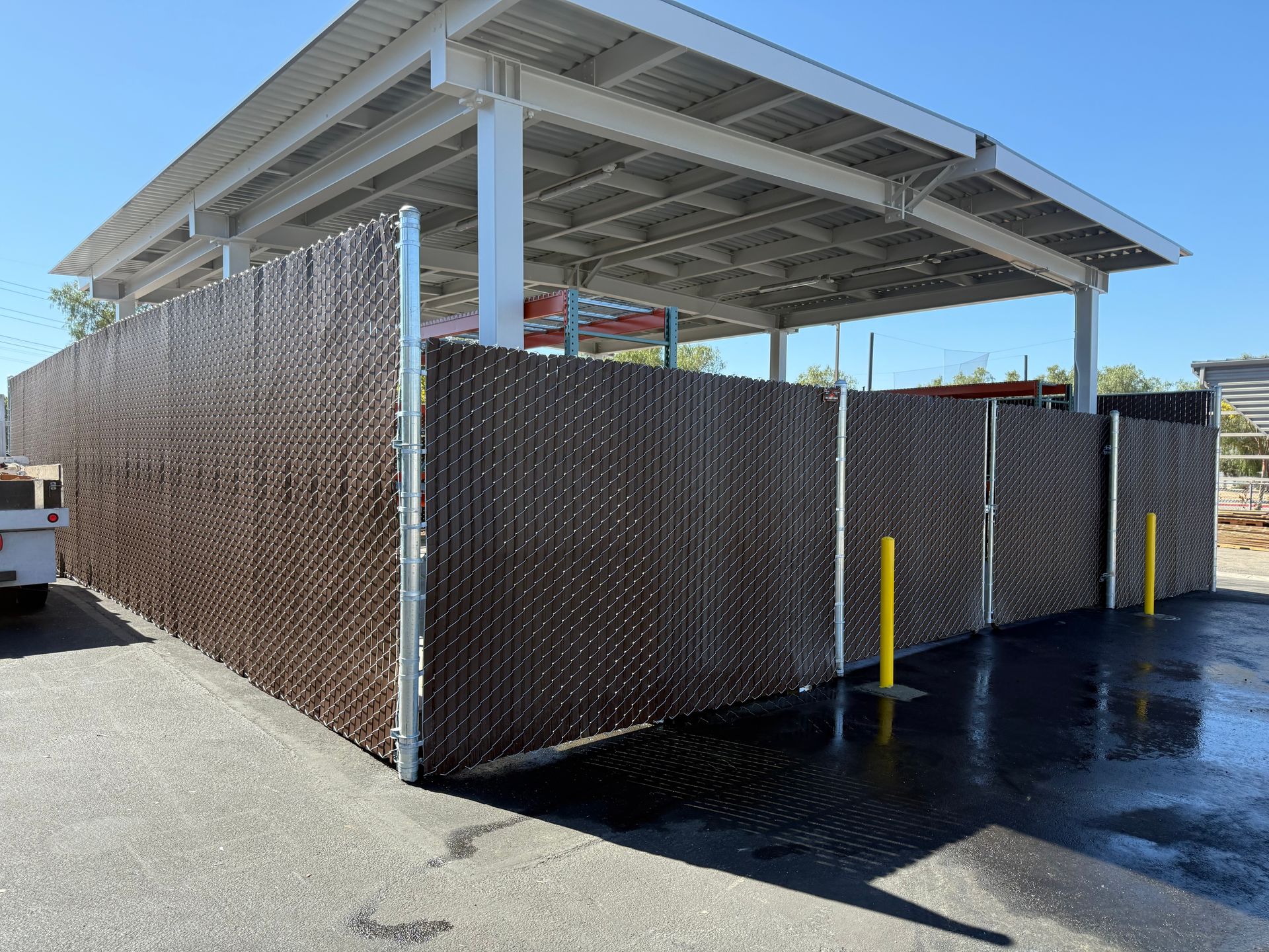 A chain link fence is surrounding a building in a parking lot.