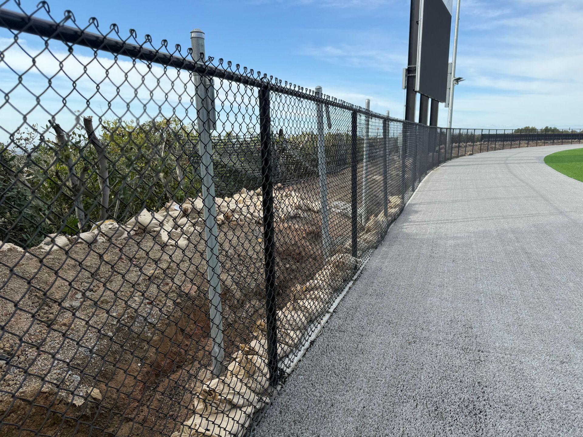 A chain link fence is along the side of a road.