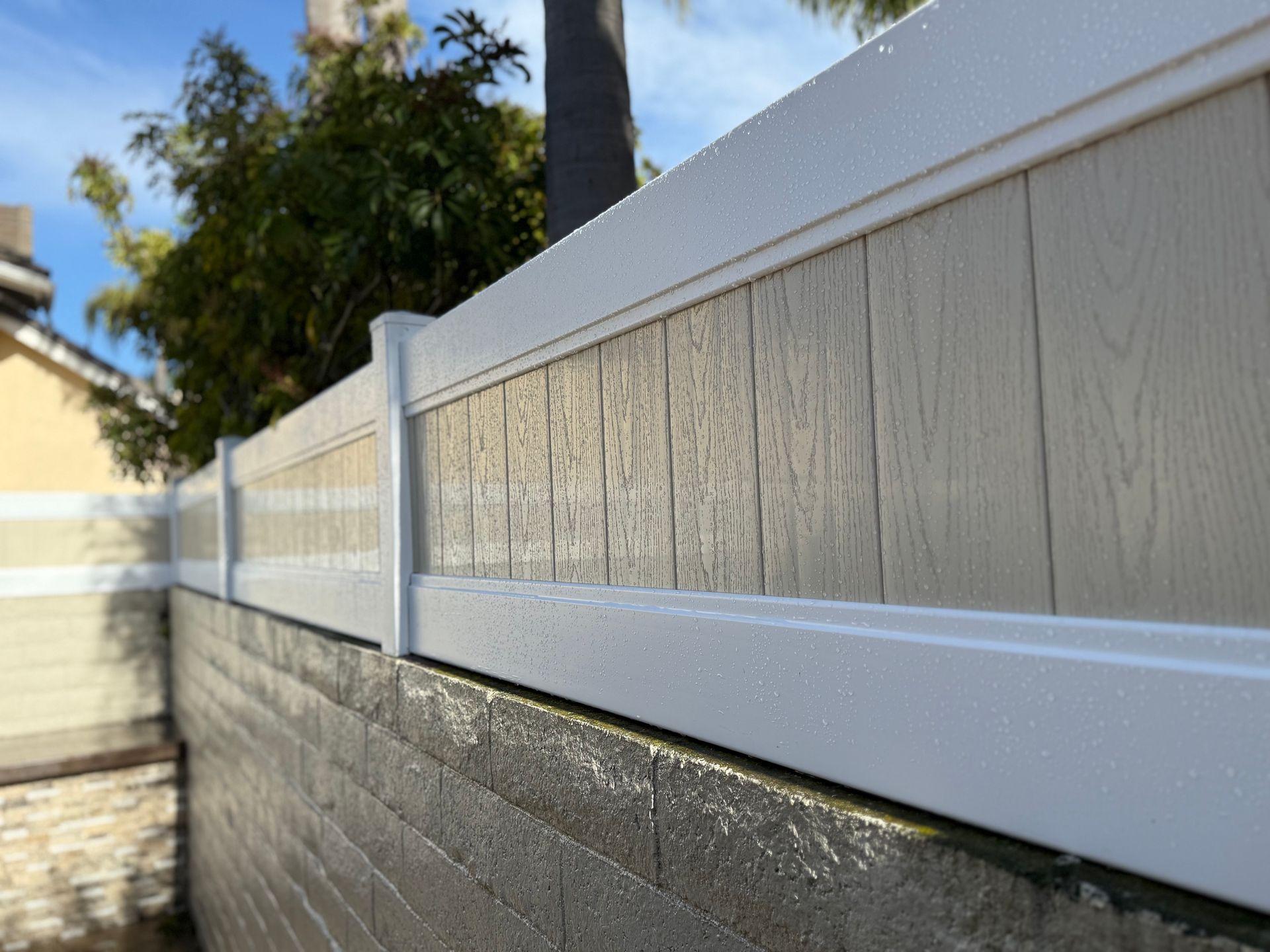 A white fence is sitting on top of a brick wall.