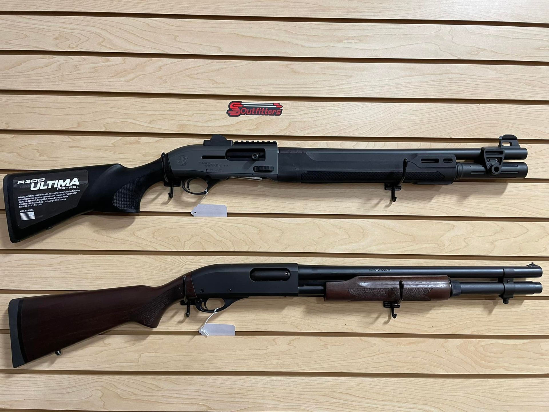 Two shotguns are hanging on a wooden wall.