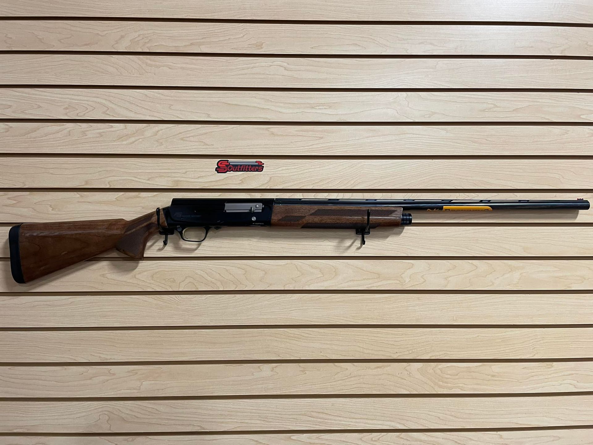  a gun is hanging on a wooden wall.