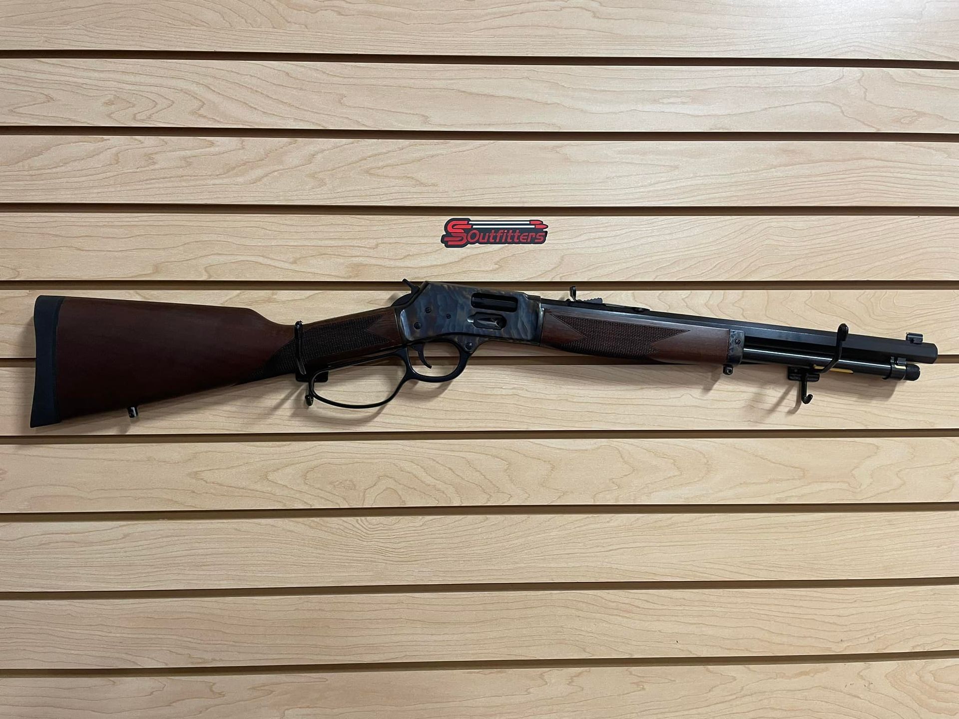  a gun is hanging on a wooden wall.