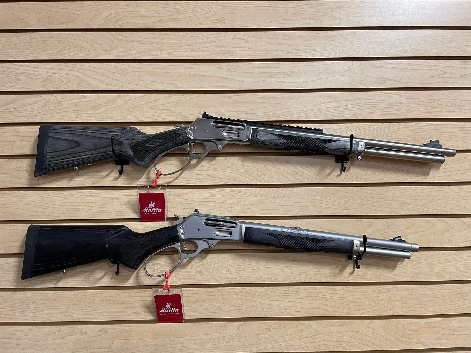 Two shotguns are hanging on a wooden wall.