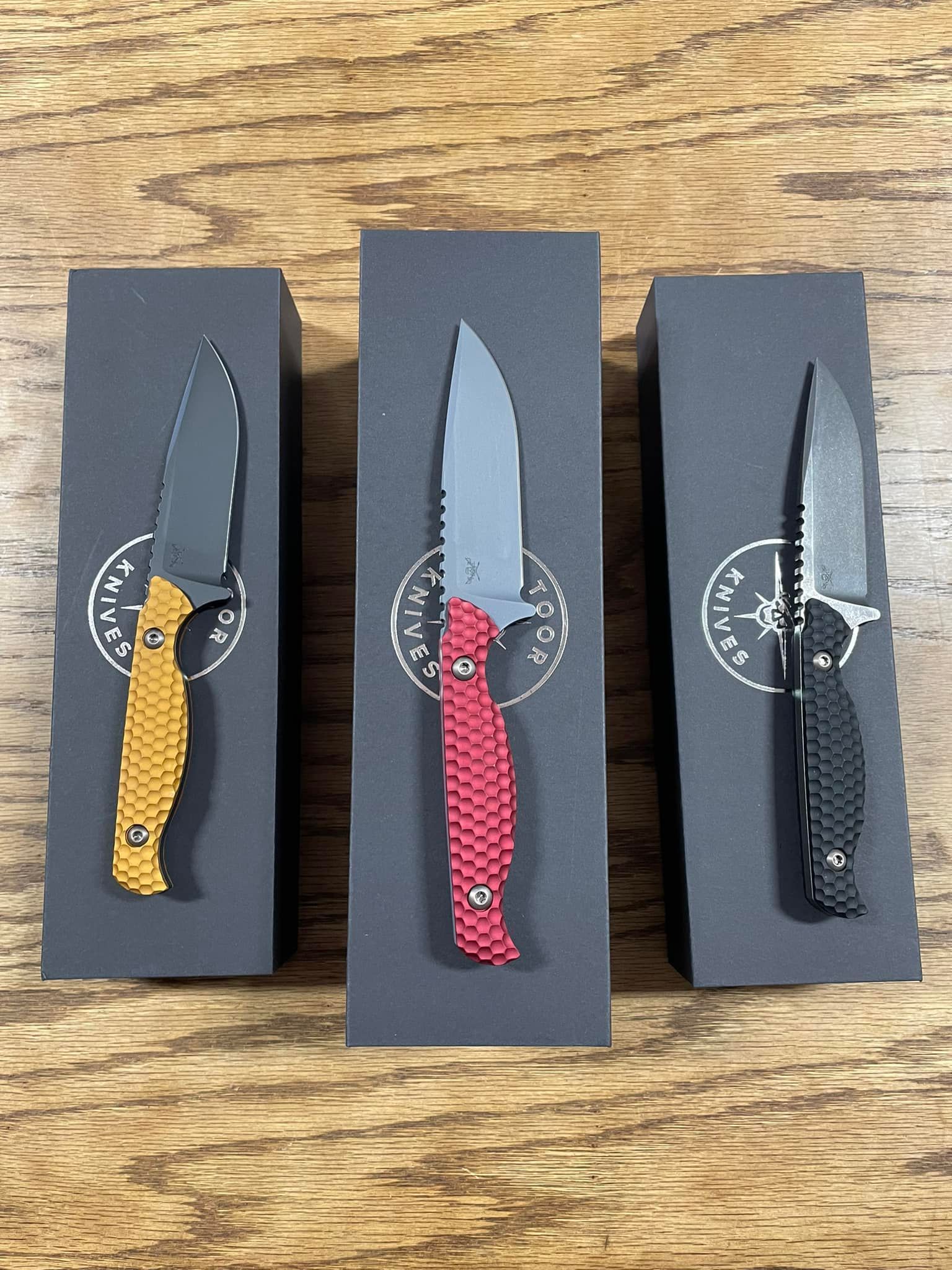 Three knives are in boxes on a wooden table