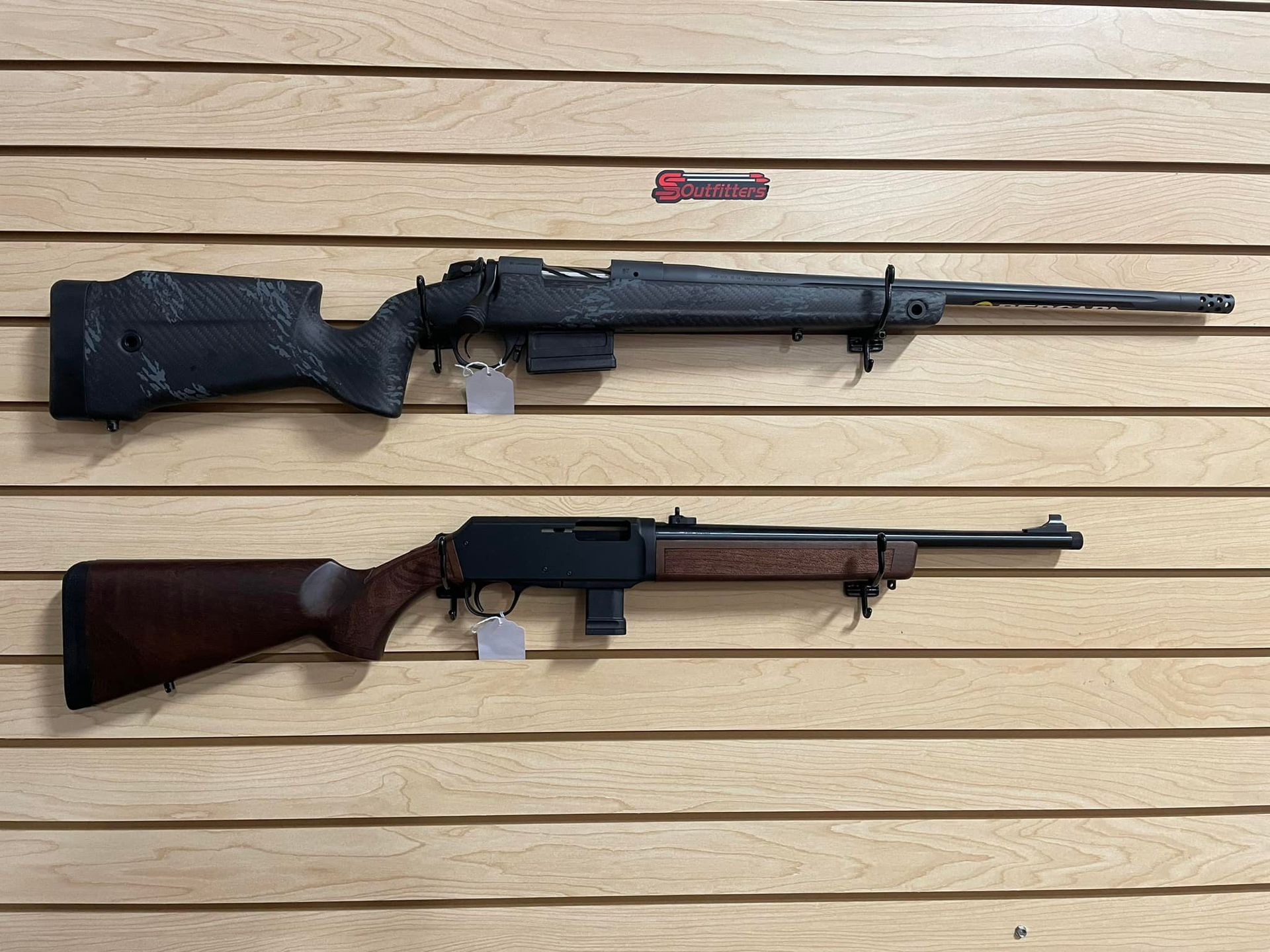 Two rifles are hanging on a wooden wall.