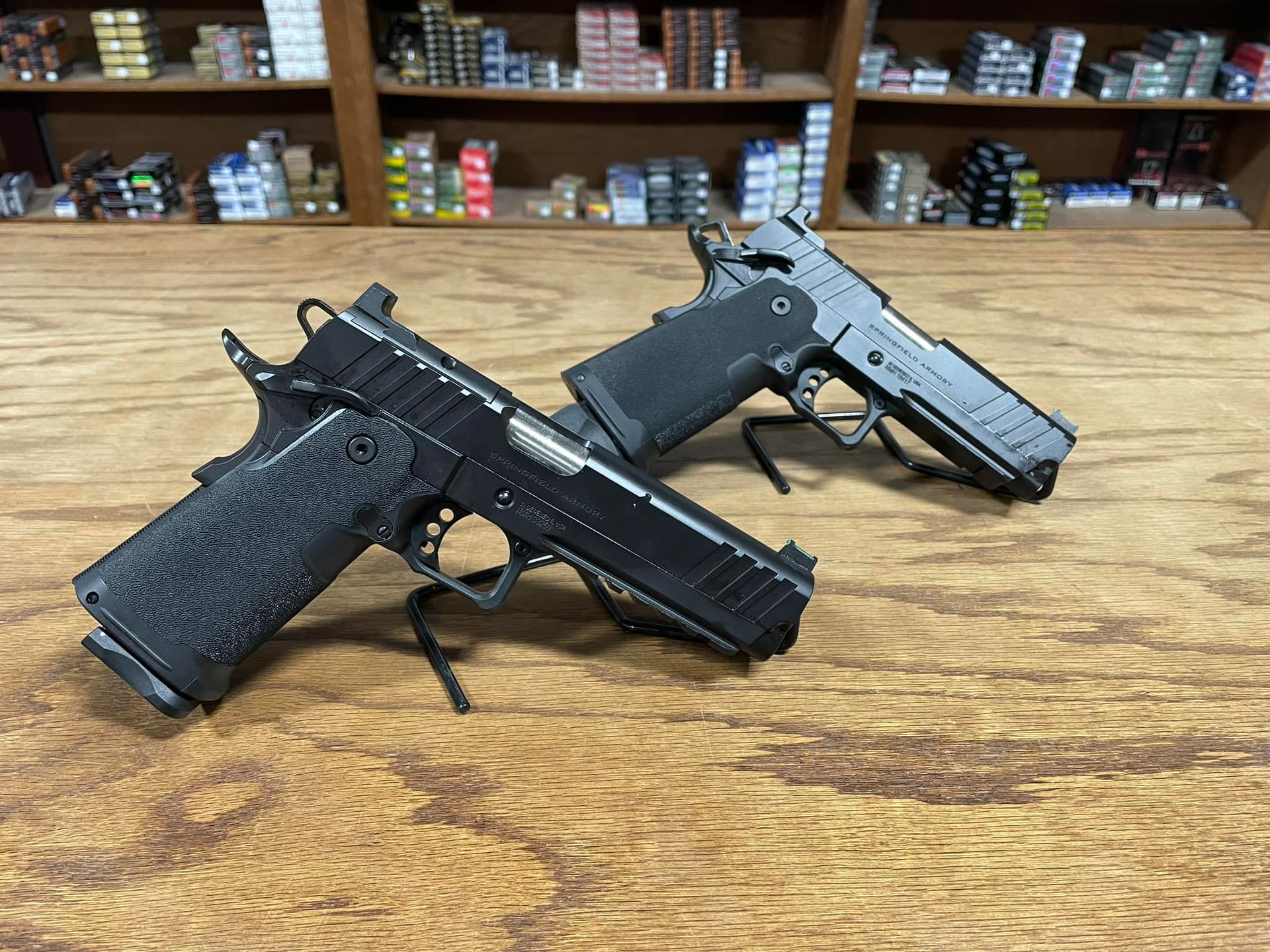 Two black pistols are sitting on a wooden table.