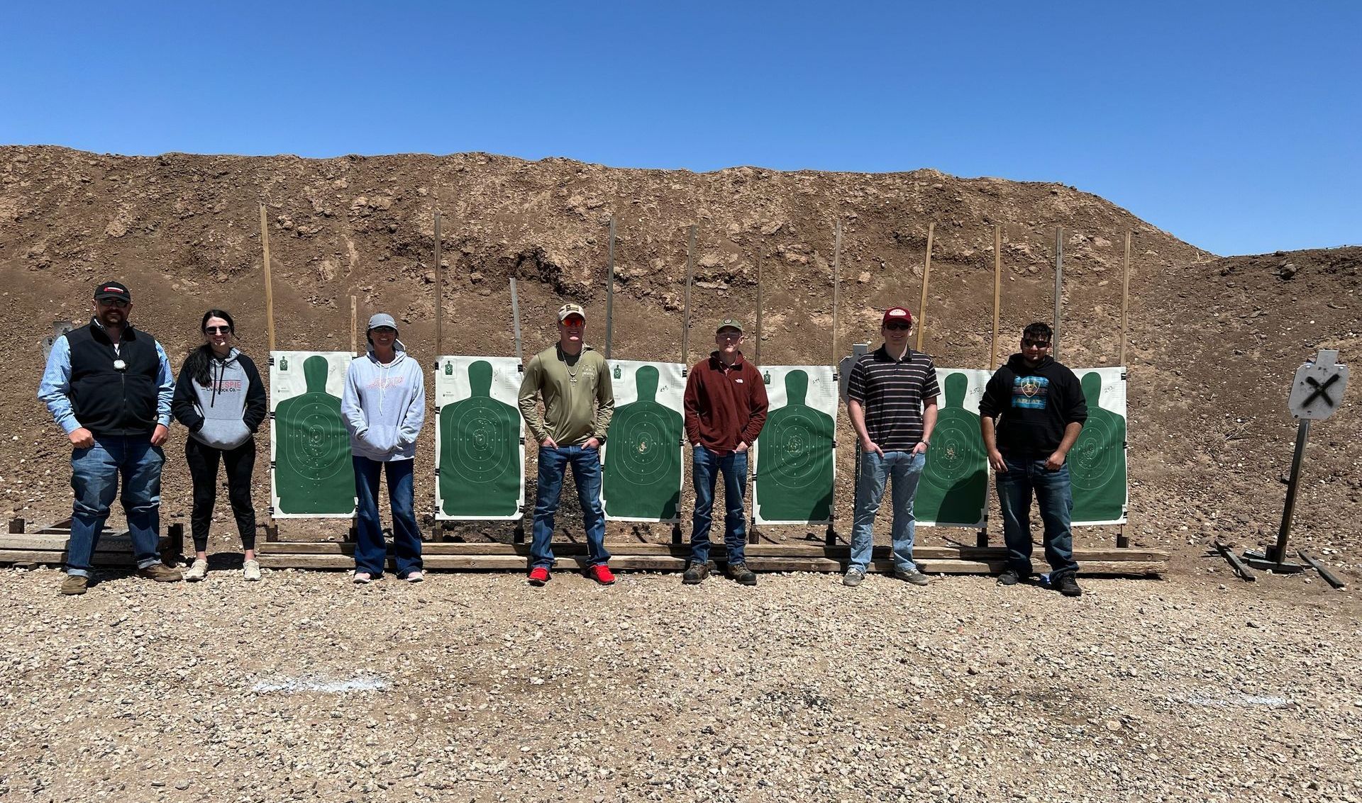 A group of people are standing in front of a row of targets.