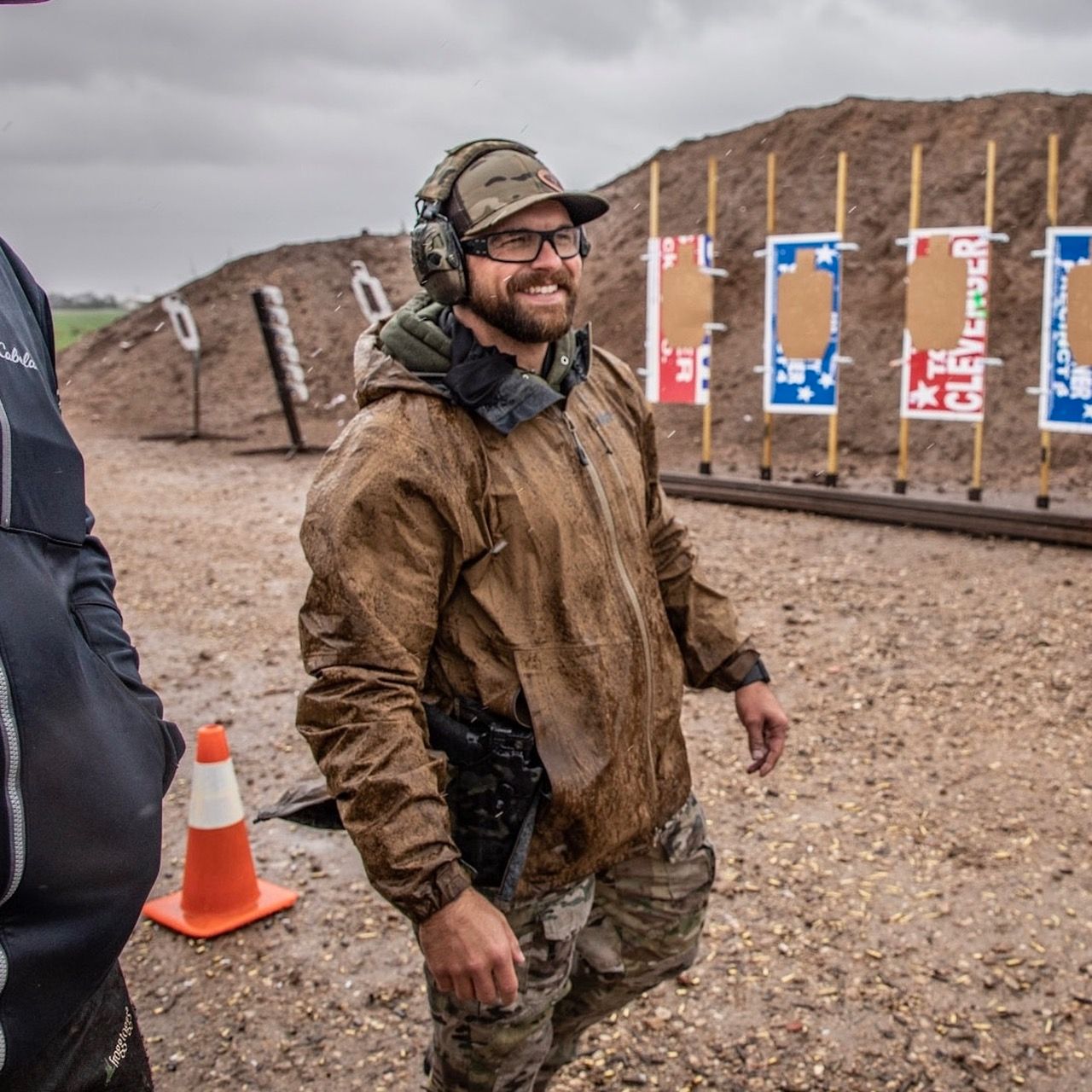A man wearing a hat and headphones is standing in front of a bunch of targets
