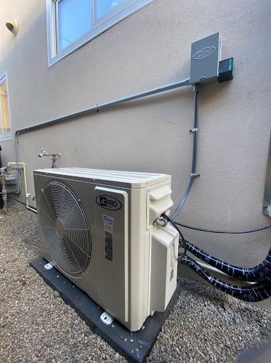 A large air conditioner is sitting outside of a building next to a window.