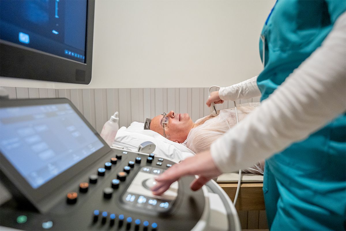Patient lying comfortably with a technician using an ultrasound probe on the chest.