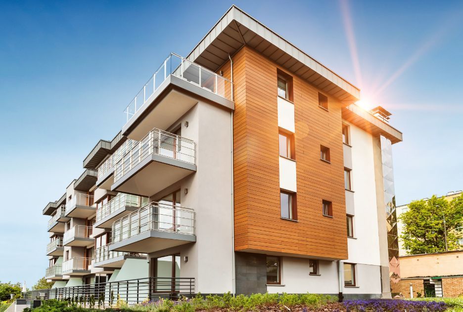 A large apartment building with balconies and a blue sky in the background.
